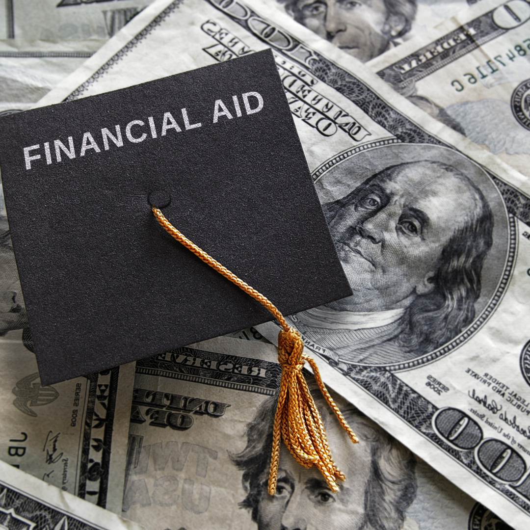 Small graduation cap with "Financial Aid" text placed on assorted cash.